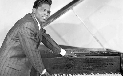 James Brown poses for a portrait beside a piano.