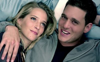Michael Buble and Debbie Timuss embrace in bed in a still from their music video.