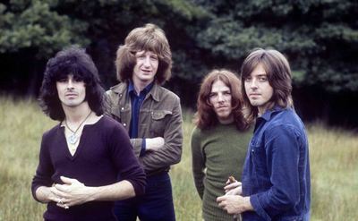 The Badfinger members pose out in a field.