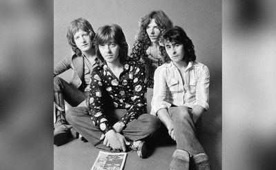 Pete Ham, Joey Molland, Mike Gibbins and Tom Evans are seated on the floor.