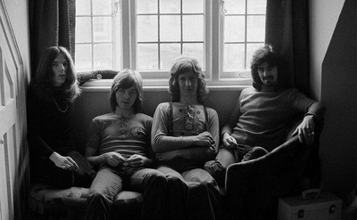 Badfinger members sit under a window.