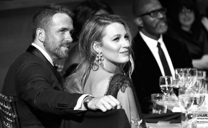 Ryan Reynolds sits next to his wife Blake Lively at an event.