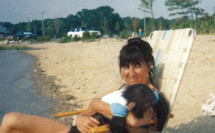 Sara Herold poses holding her baby chimpanzee at the beach.