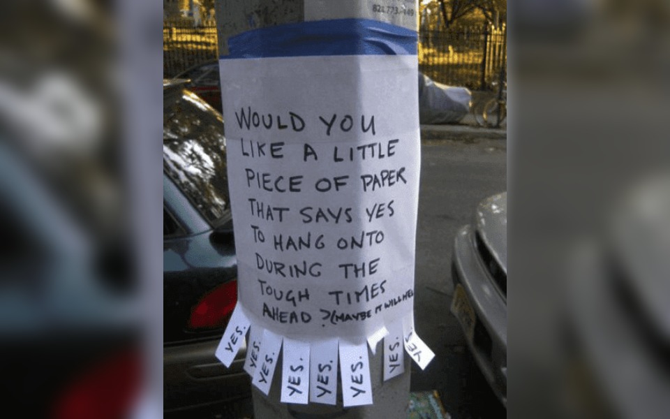 A street poster saying "would you like a piece of paper"