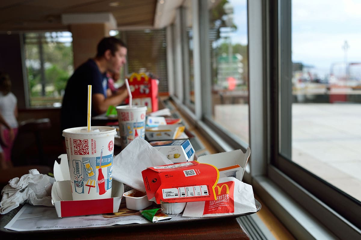 McDonald's restaurant table filled with trays from the end of multiple customers' meals. 