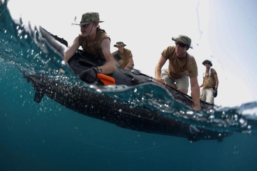 Soldiers holding a torpedo underwater