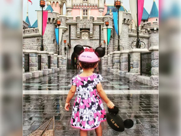  Little girl holding her brother’s hat on Disney Land