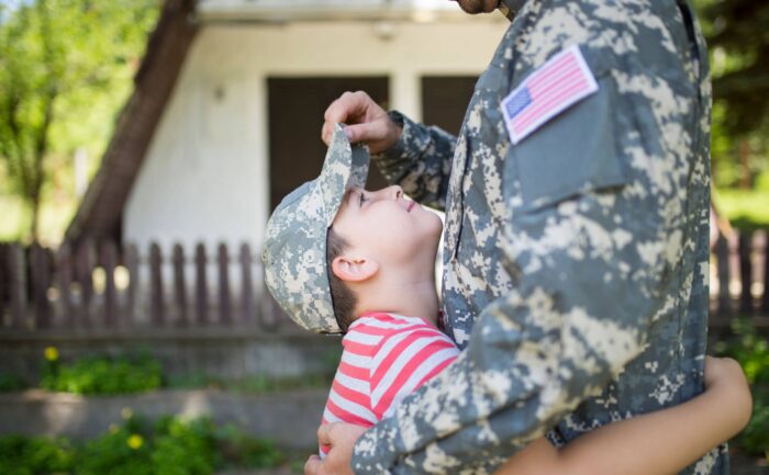 A soldier dad hugs his son.