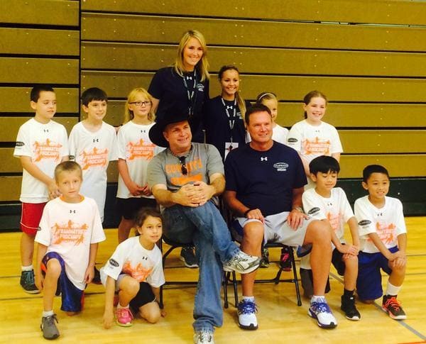 Garth Brooks and Bill Self working with kids basketball team. 