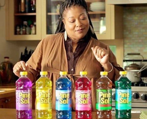 Diane Amos standing in the kitchen in front of six different colored bottles of Pine-Sol.