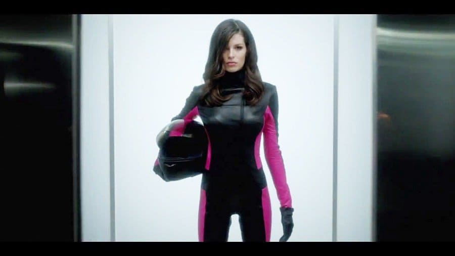Carly Foulkes in a black and hot pink jumpsuit holding a helmet.