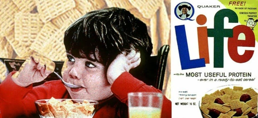 Photograph of Little Mikey eating Life cereal with a box of it next to him.