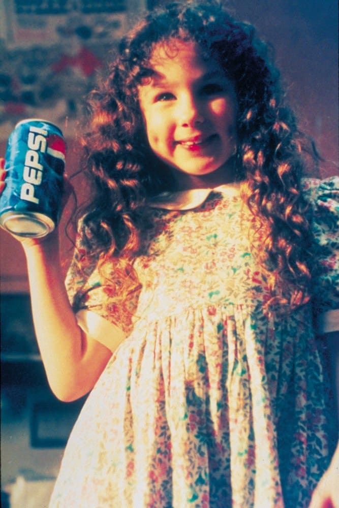 Hallie Eisenberg as a young girl holding up a can of Pepsi.