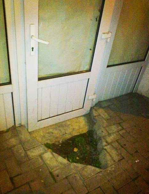 A hole in the floor next to a door