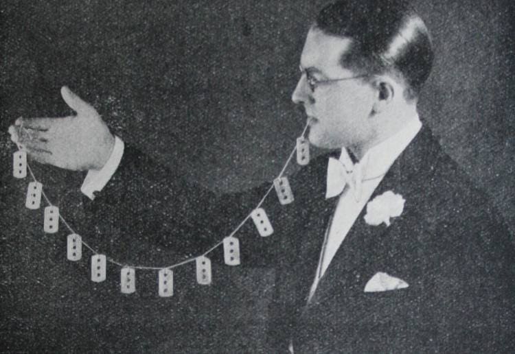 Harry Houdini holding razors on a string in his mouth