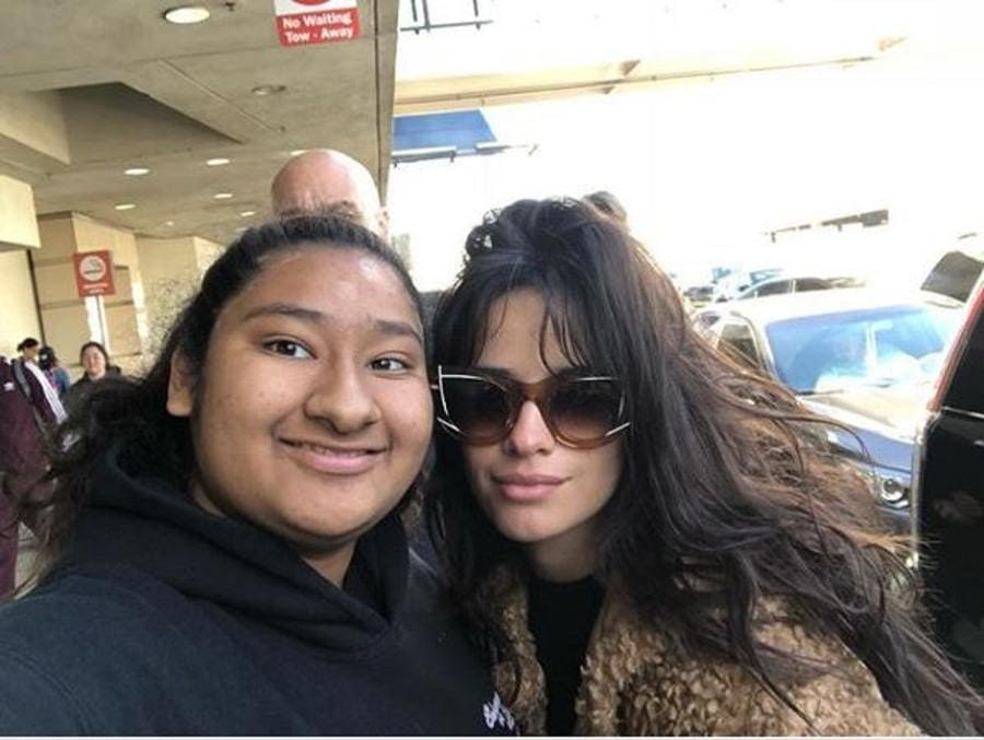 Camila Cabello is posing with her sunglasses on the outside of the airport with Marlen.