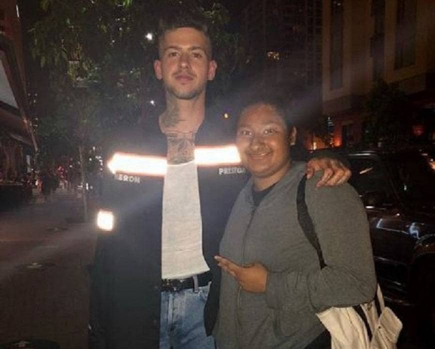 Photograph of Travis Mills while he is standing with Marlen in the street, who is holding her fingers up with a peace sign.