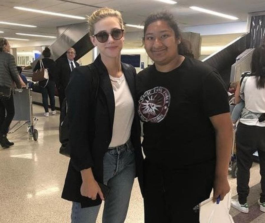 Lili Reinhart and Marlen Orozco are posing for a photograph next to the baggage claim at the airport.