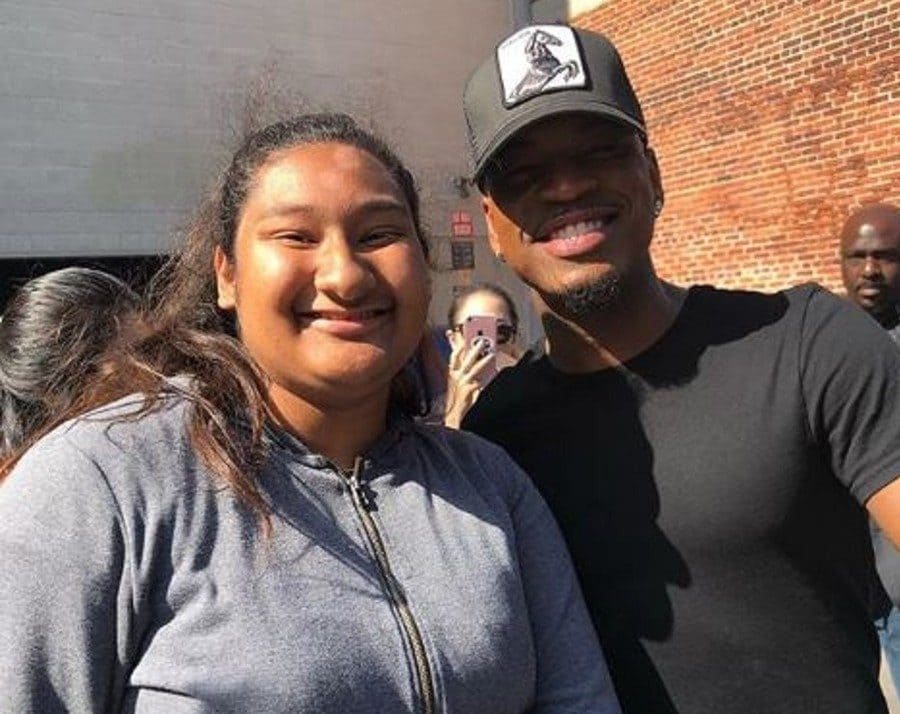 Ne-Yo posing with Marlen are outside of a building near a red brick wall.