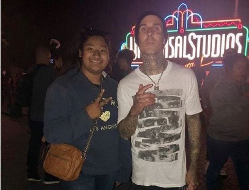 Travis Barker and Marlen Orozco are posing with their hands as a peace symbol.