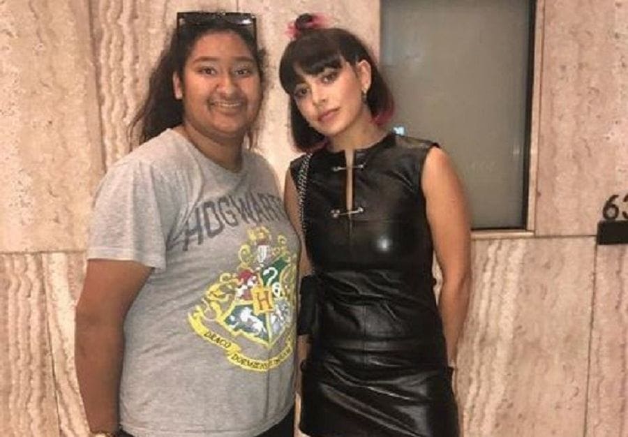 Charli XCX is photographed in a black leather dress and leather boots next to Marlen in a cute Hogwarts t-shirt.