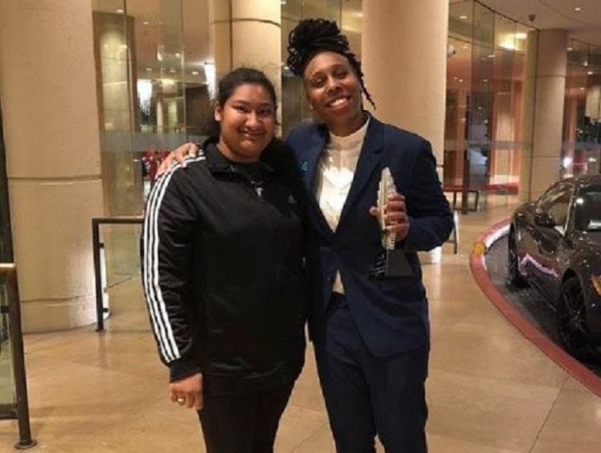 Lena Waithe is holding an award while posing with Marlen for a photograph outside of a hotel.