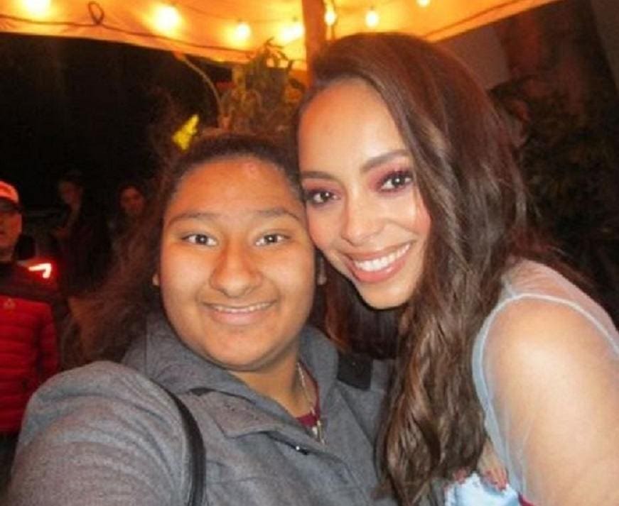 Amber Stevens West and Marlen Orozco are posing under an umbrella with a string of white lights.