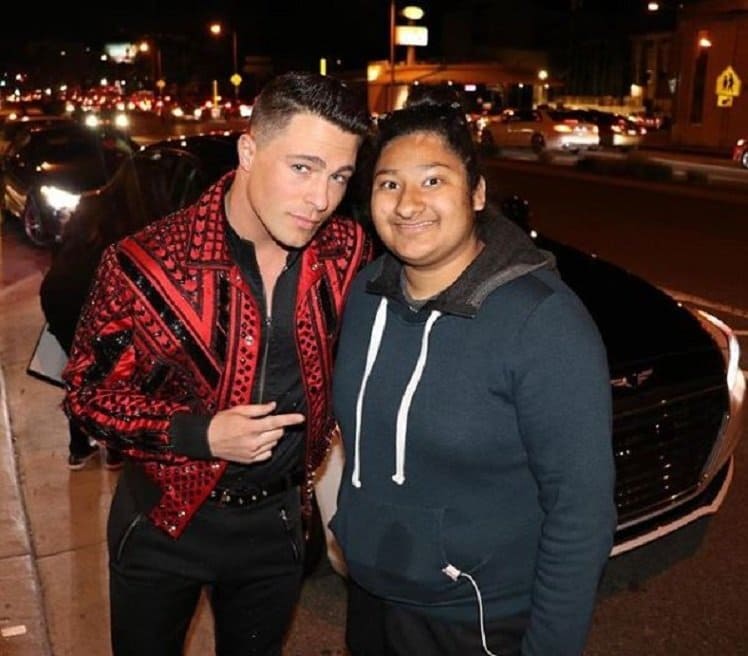 Colton Haynes and Marlen are posing in front of a sleek black town car.