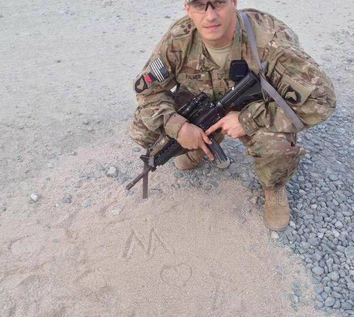 Tyler Palmer in uniform sitting in the sand next to where he drew ‘M heart T.’