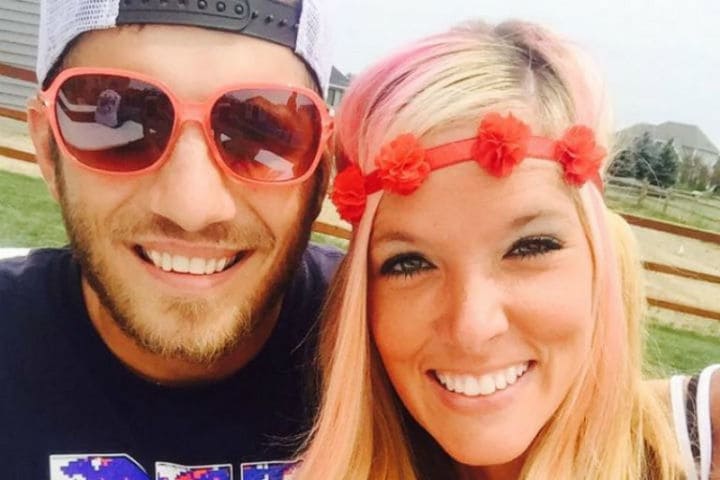 Mandi and Tyler taking a selfie sitting in front of a grassy area.
