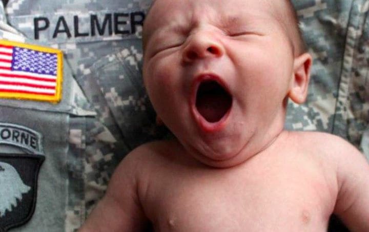 Photo of the new baby yawning while leaning on Tyler’s uniform.