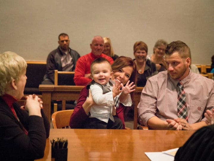 Mandi holding Hunter in the courtroom while he claps.