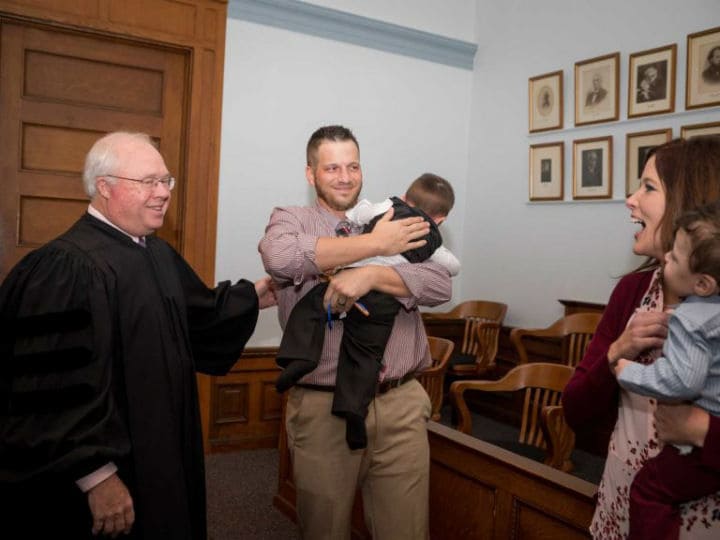 Tyler holding Hunter while speaking to the judge.