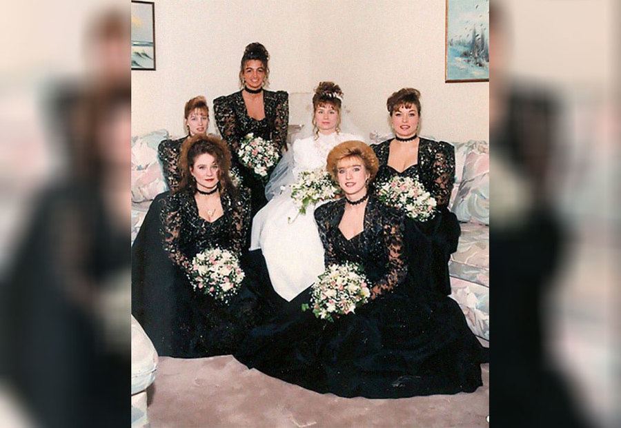 A bride wearing a dress and her bridesmaids wearing black 