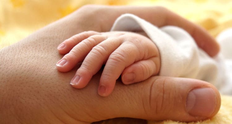 A baby’s hand holding his mother's hand