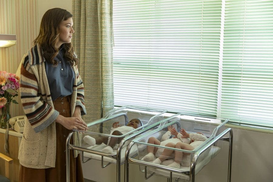 Rebecca Pearson standing with the three twin babies in her hospital room.