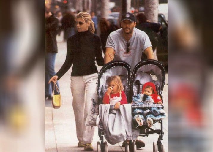 Tim McGraw and Faith Hill with their two little daughters walking on a street.