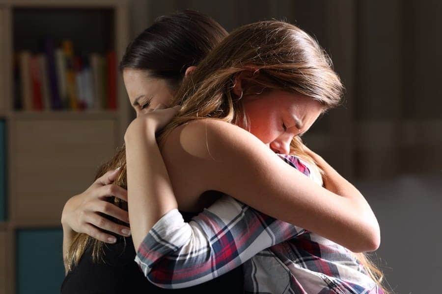 Stock photo of two women hugging in a dark room.