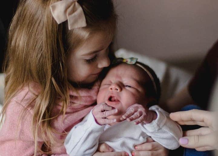 Toddler girl holding a baby girl.