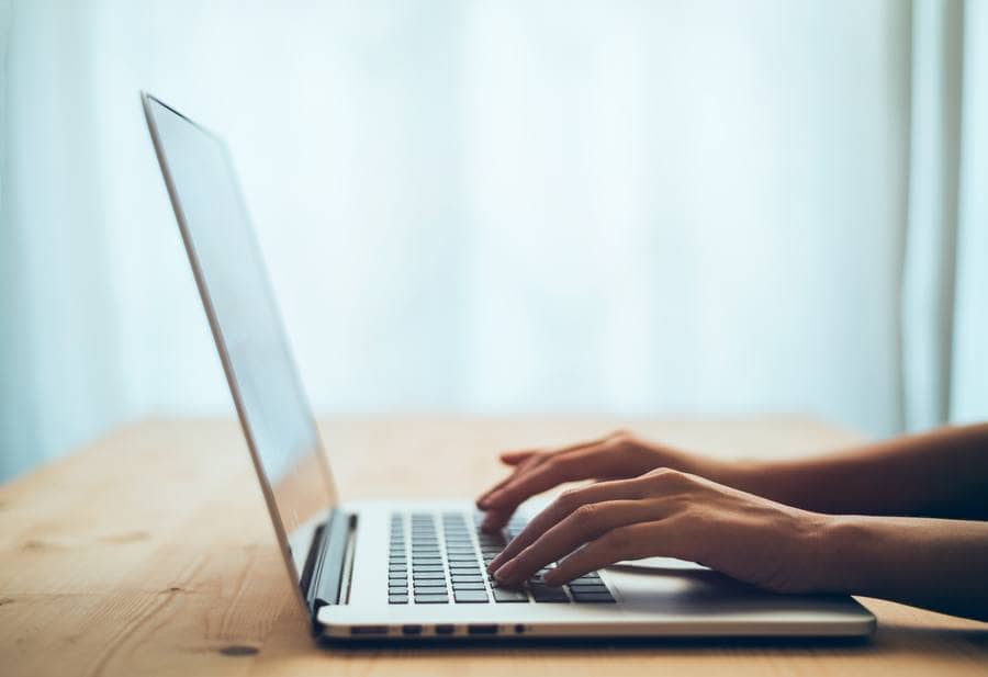 Stock photo of a woman's hands typing on a laptop keyboard.