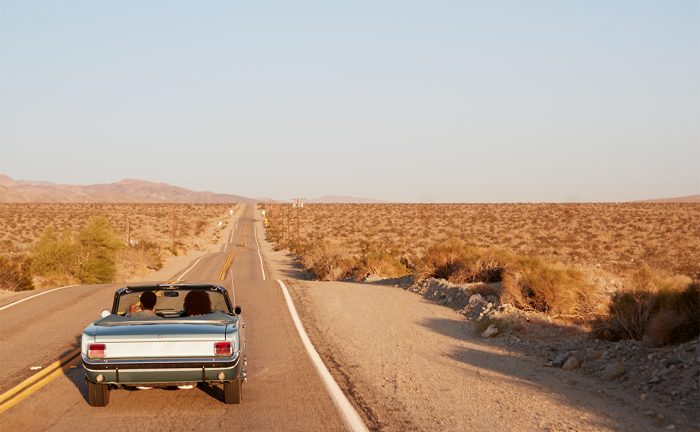 A car on an open road with desert all around