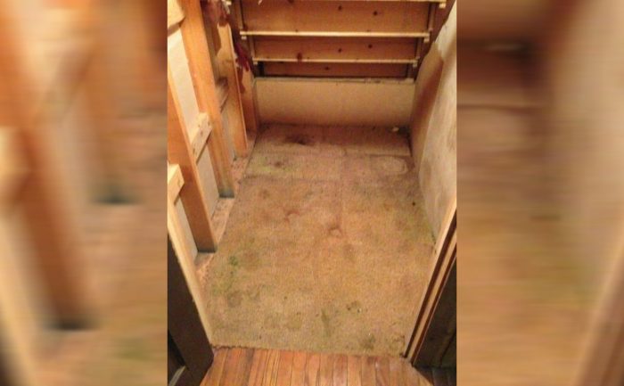 An old staircase with a patch of carpet underneath it