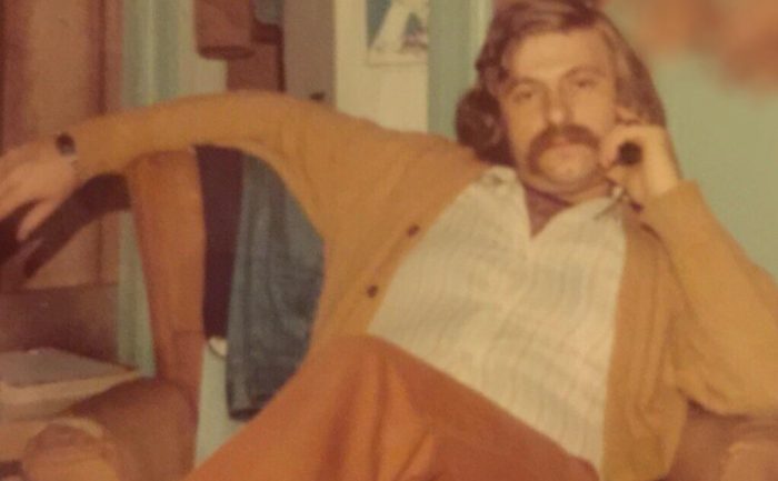 A middle aged man sitting on an armchair back in the day
