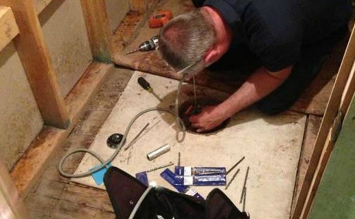 A man trying to remove concrete from around a hole