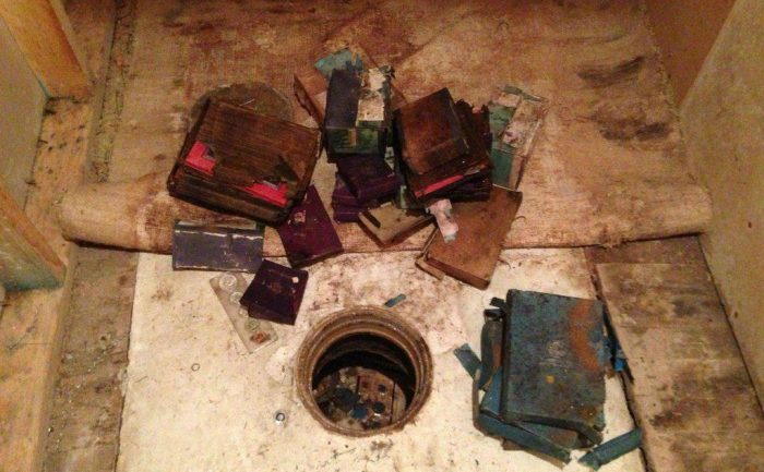 The hole in the floor surrounded by old books and a few coins