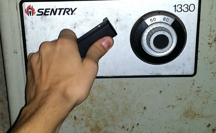 A man with his hand on the handle of a safe