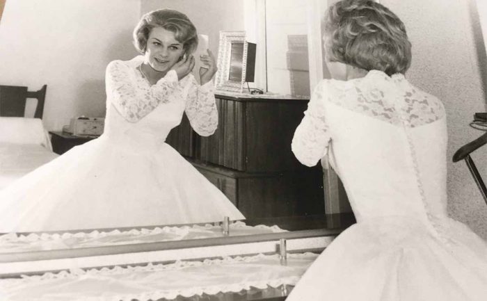 vintage wedding photo of the bride putting on jewelry