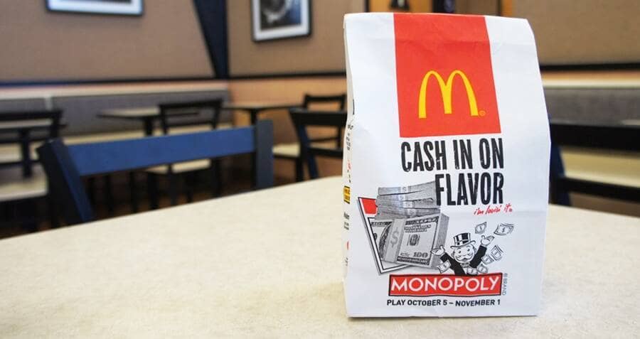 A photograph of a McDonald’s takeaway bag with the Monopoly game ad and ‘Cash in on Flavor’ written on it.