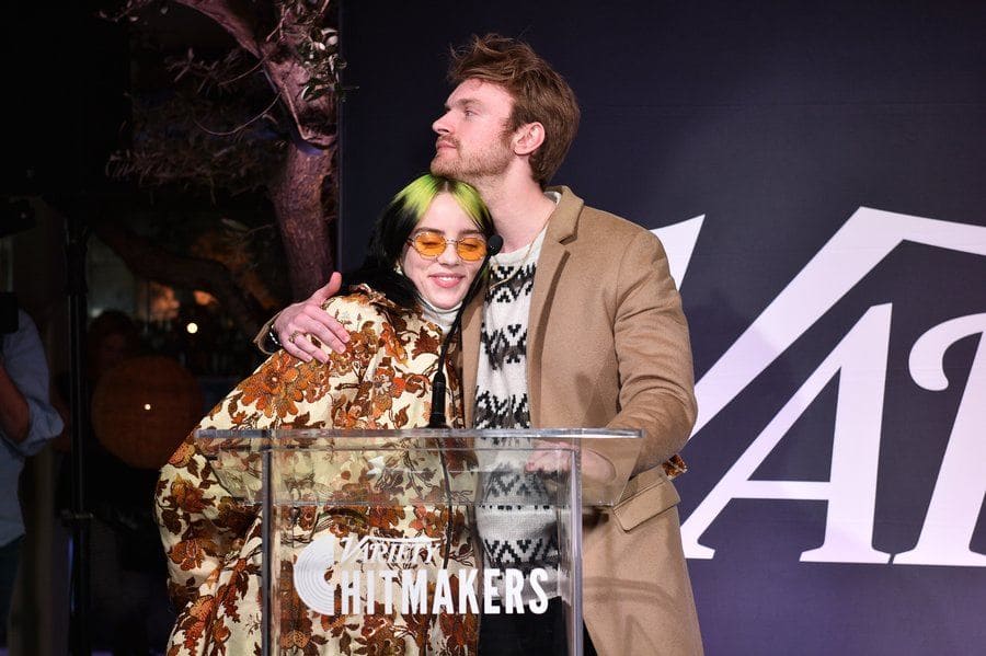 Finneas O'Connell and Billie Eilish at the Variety Hitmakers Brunch embracing behind the podium. 