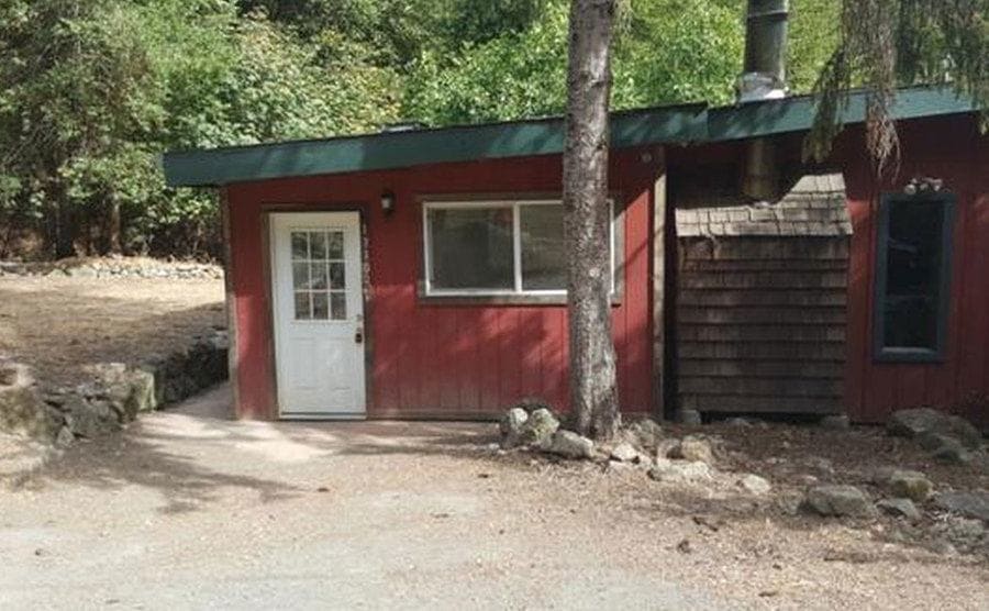 A photograph of a red shack in the woods